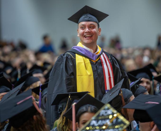 CU Denver graduate smiling in the commencement crowd