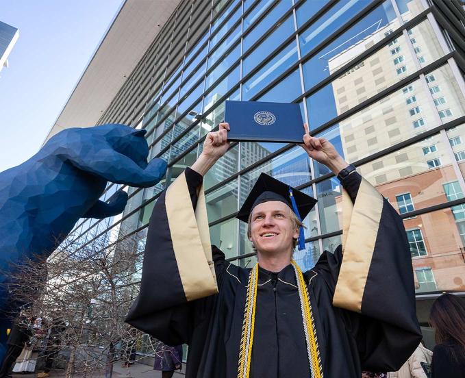 CU Denver outside of Colorado Convention Center after commencement holding up diploma