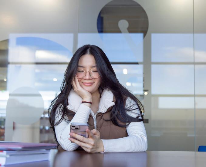 CU Denver student smiling while looking at phone