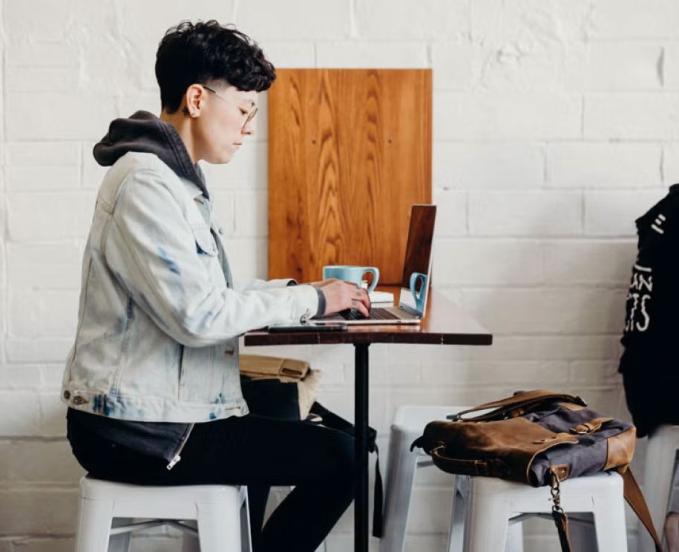 CU Denver online student in cafe with laptop