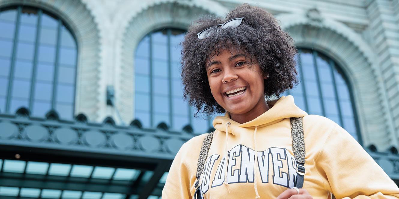 CU Denver student wearing gold CU Denver hoodie with a backpack