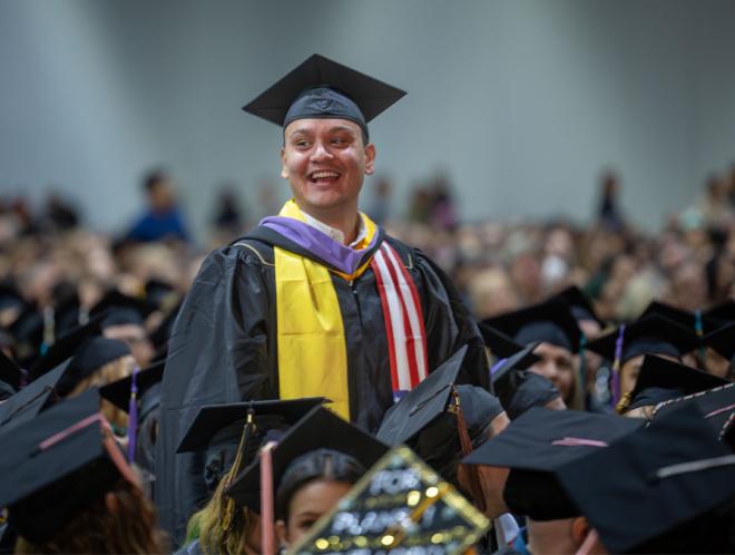 CU Denver graduate smiling in the commencement crowd