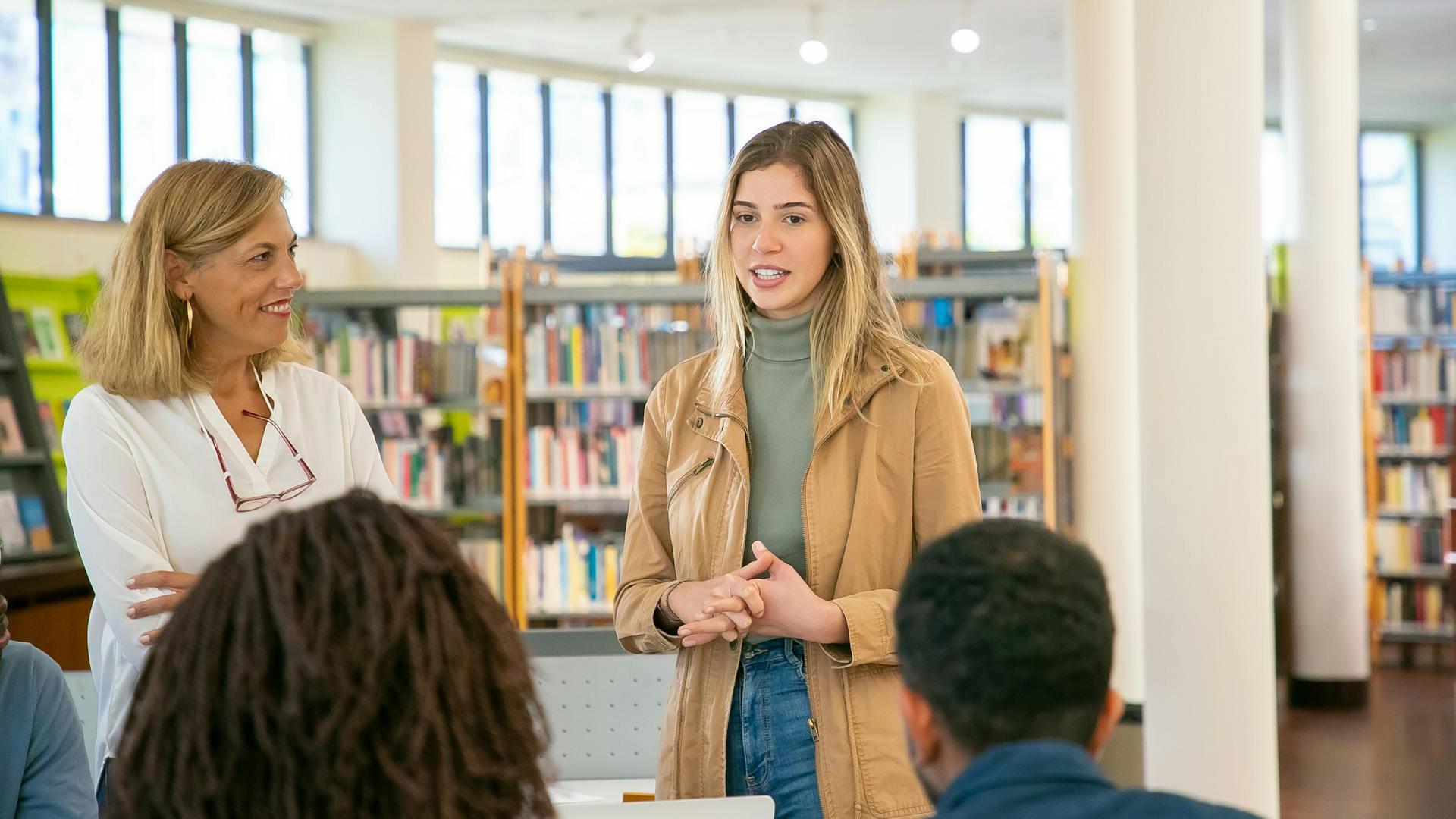 Teacher in library addressing high school students