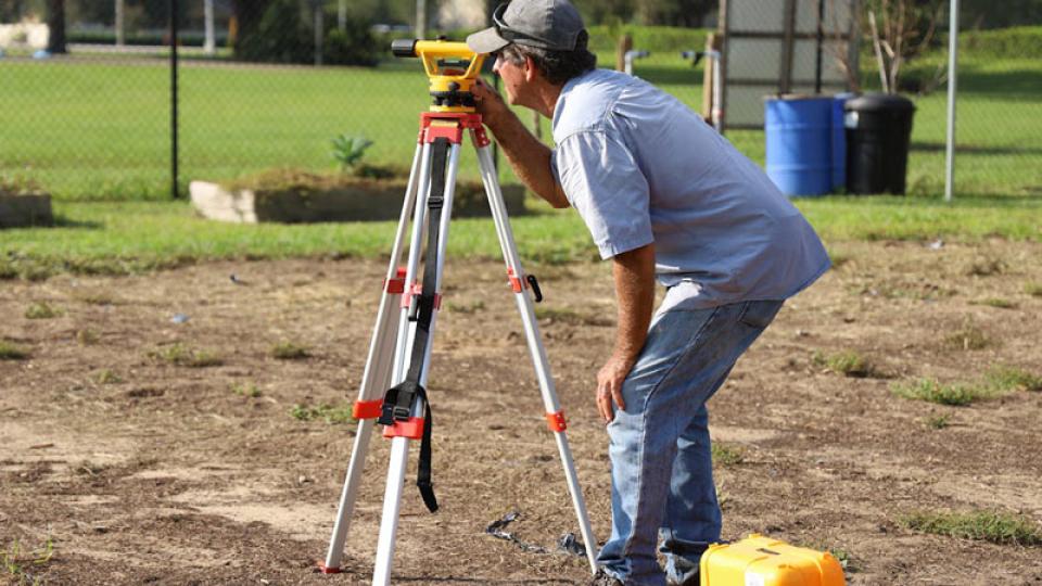 Man using electronic distance measurement (EDM) to complete a land survey