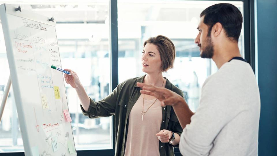 Business professionals discussing notes during operations meeting