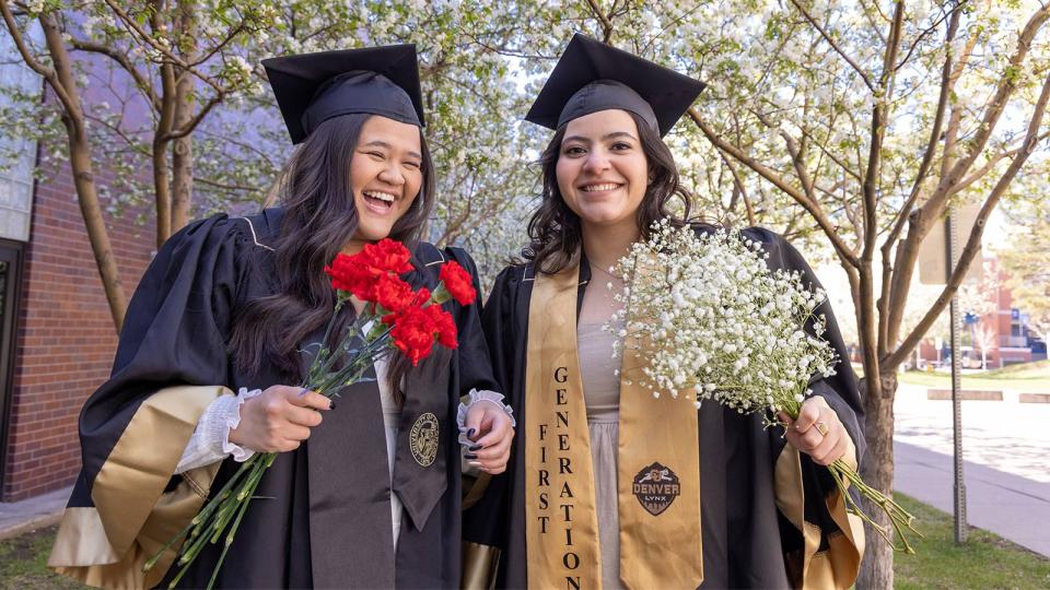 CU Denver students in regalia wearing first gen stole and holding flowers