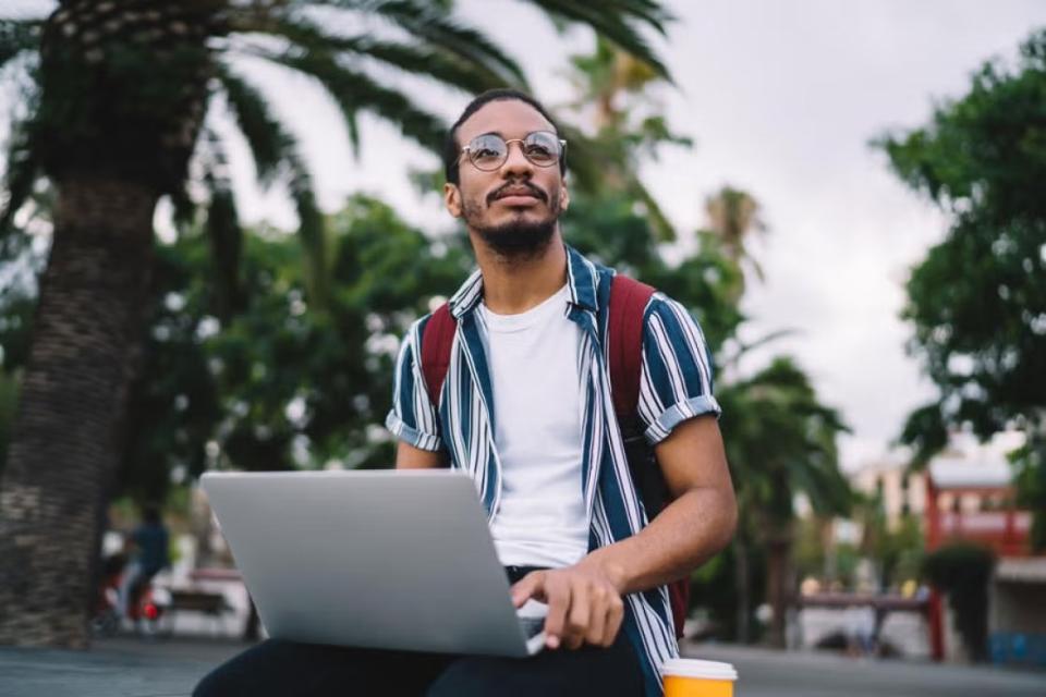 CU Denver online student working outside on laptop