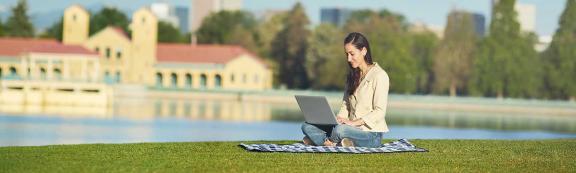 Woman sitting in park studying with laptop.