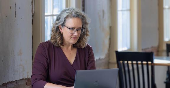 Woman sitting at table working on laptop